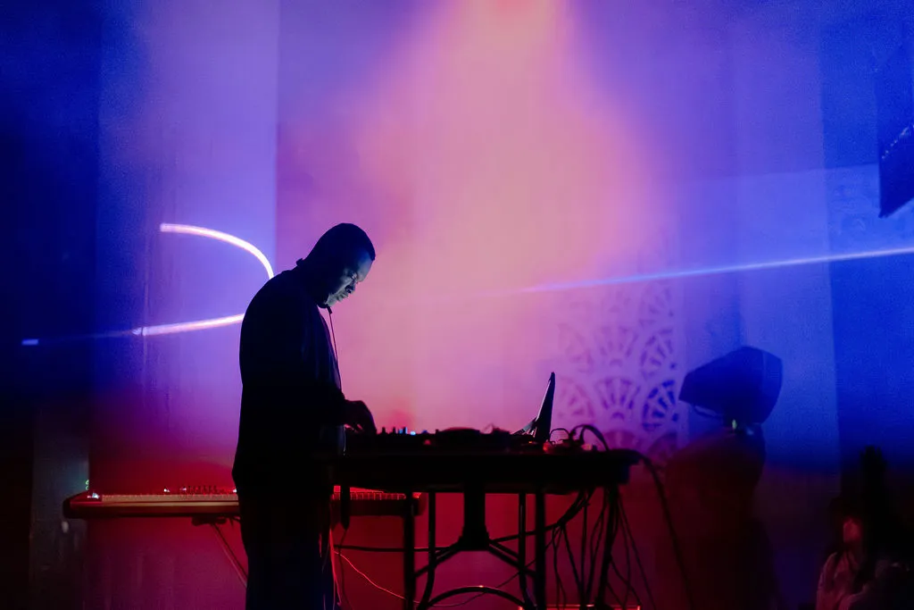 Performer silhouetted with the laser path carrying the room